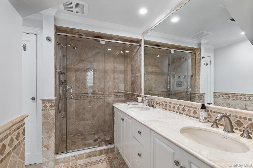 94 Round Hill Road Scarsdale, NY 10583 - Photo 24 of 46 The primary bathroom features dual sinks and an oversized glass-enclosed shower.