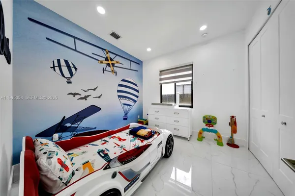 a bedroom with a bed and a flat tv screen on dresser