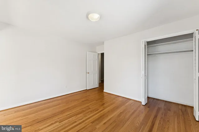 a view of an empty room with wooden floor and closet