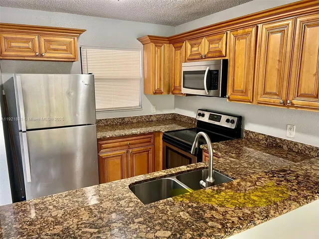a kitchen with granite countertop a sink stainless steel appliances and cabinets