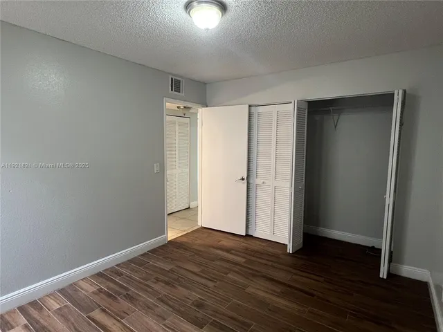 a view of an empty room with wooden floor and closet