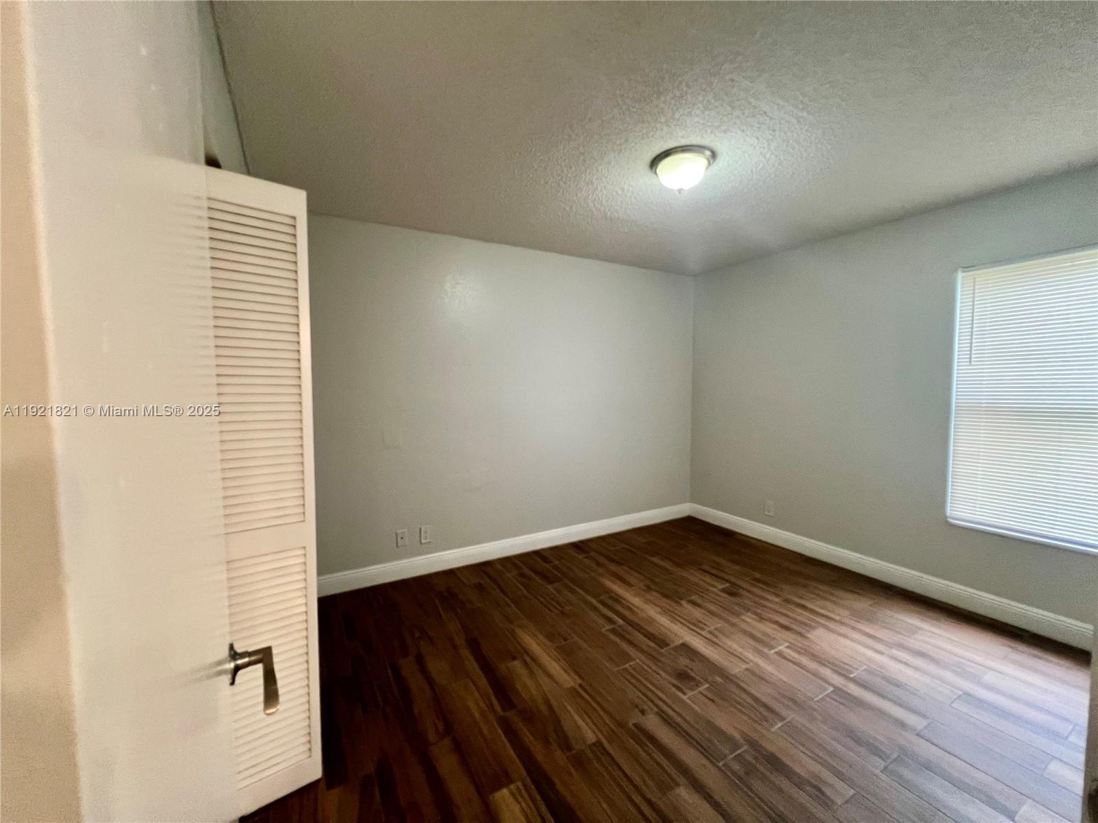 1477 Lake Crystal Drive, Unit F West Palm Beach, FL 33411 - Photo 12 of 16 an empty room with wooden floor and windows