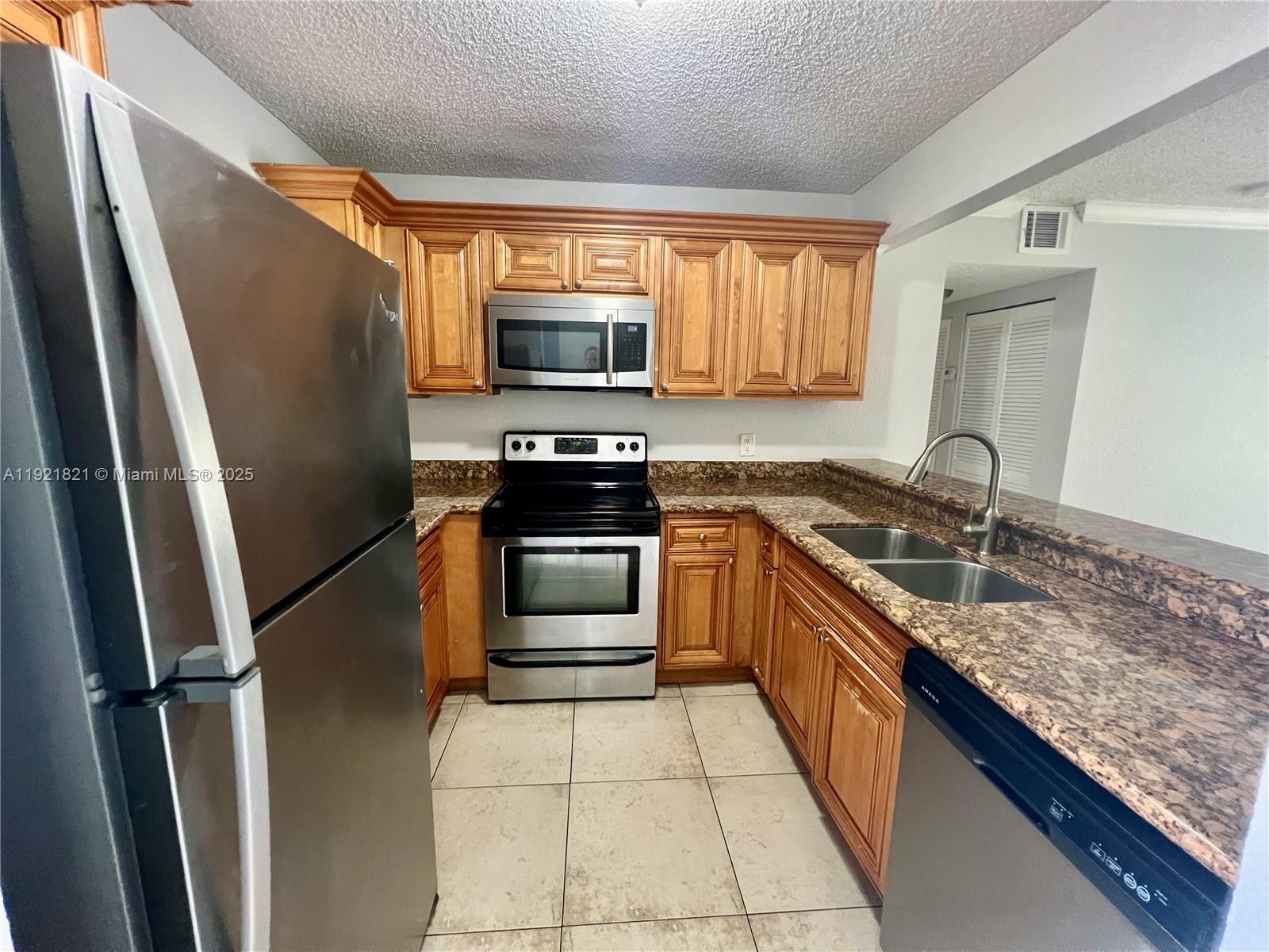 1477 Lake Crystal Drive, Unit F West Palm Beach, FL 33411 - Photo 3 of 16 a kitchen with stainless steel appliances granite countertop a refrigerator stove and sink