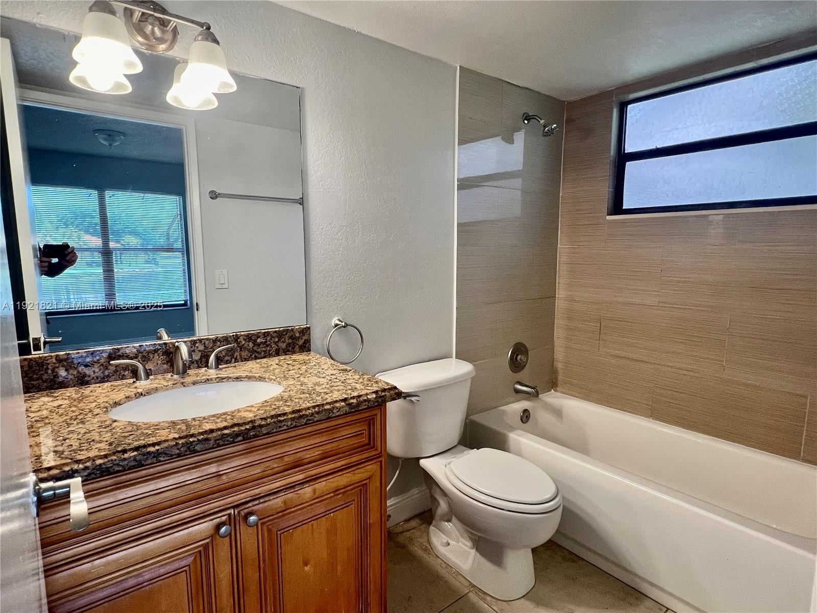 1477 Lake Crystal Drive, Unit F West Palm Beach, FL 33411 - Photo 9 of 16 a bathroom with a granite countertop sink toilet and shower
