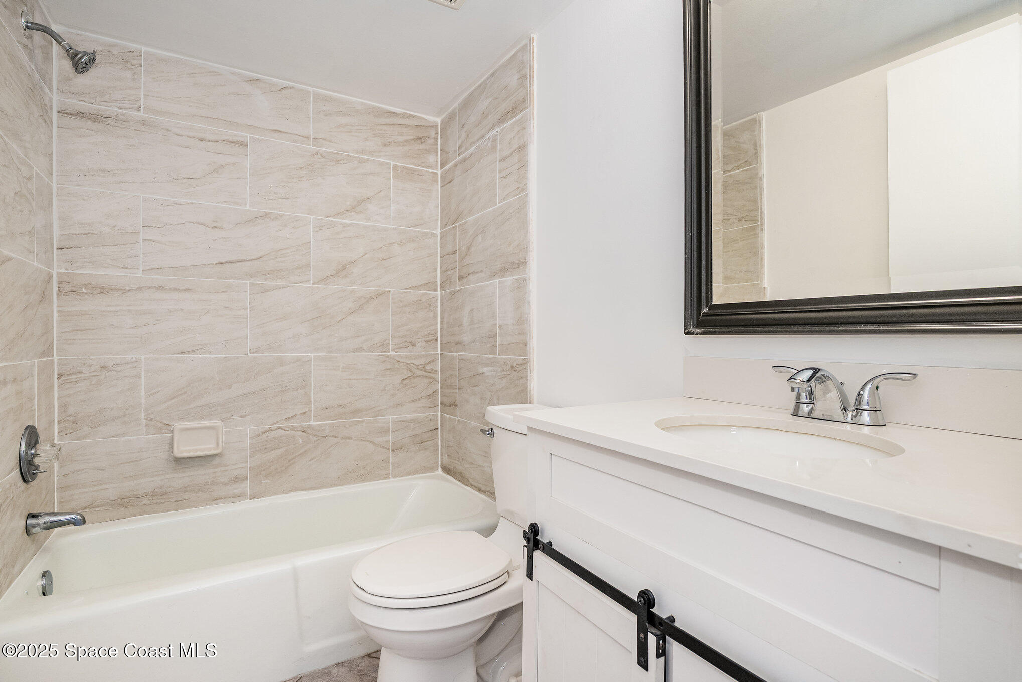 205 Palmetto Avenue, Unit 410 Merritt Island, FL 32953 - Photo 12 of 19 a bathroom with a sink a toilet a mirror a bathtub and shower