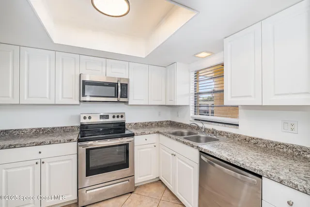 a kitchen with granite countertop white cabinets white stainless steel appliances and a sink