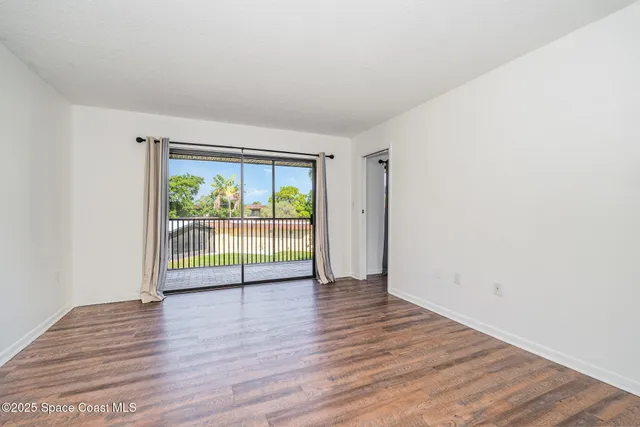 an empty room with wooden floor and outdoor view
