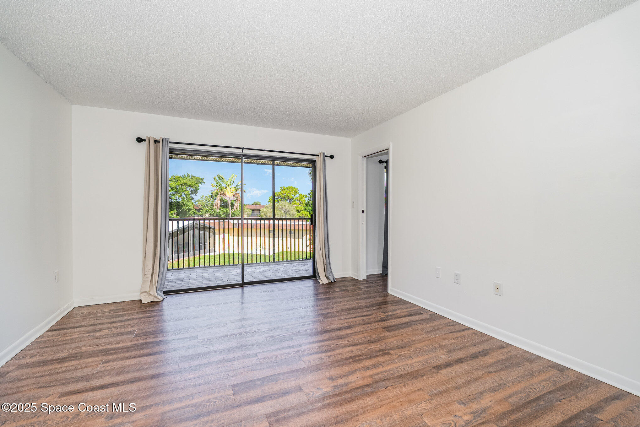205 Palmetto Avenue, Unit 410 Merritt Island, FL 32953 - Photo 8 of 19 an empty room with wooden floor and outdoor view
