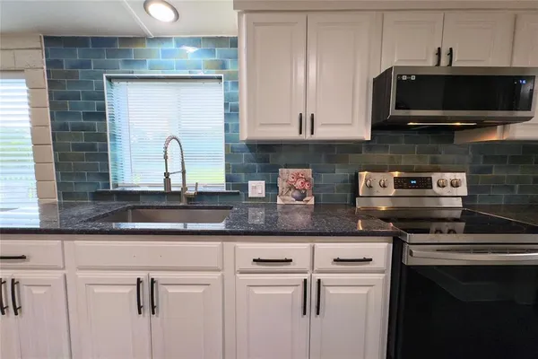 a kitchen with stainless steel appliances granite countertop a sink and a microwave