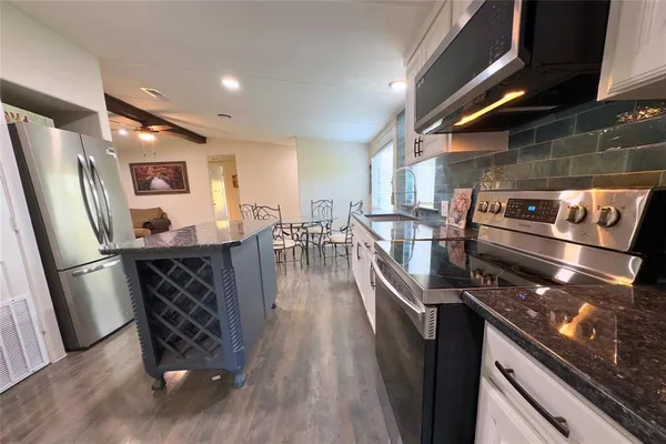 a kitchen with granite countertop a refrigerator stove and sink