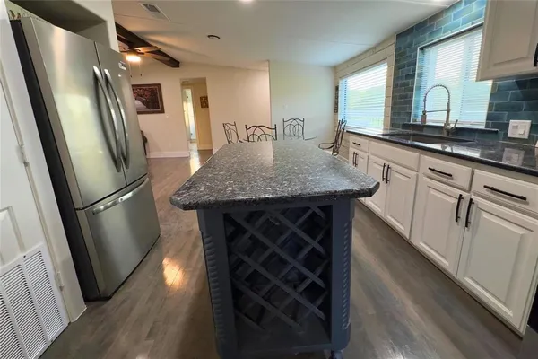 a kitchen with stainless steel appliances granite countertop a refrigerator a sink a stove and white cabinets