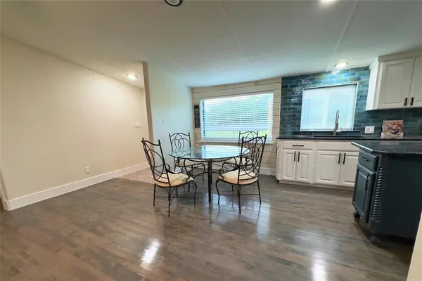 a kitchen with stainless steel appliances a dining table chairs and a wooden floor