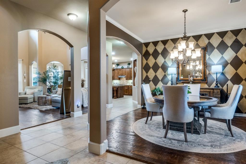 2810 Baker Street Sachse, TX 75048 - Photo 3 of 26 Dining area featuring an accent wall, light tile patterned flooring, crown molding, a chandelier, and arched walkways