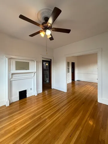 a view of a livingroom with a fireplace a ceiling fan and wooden floor