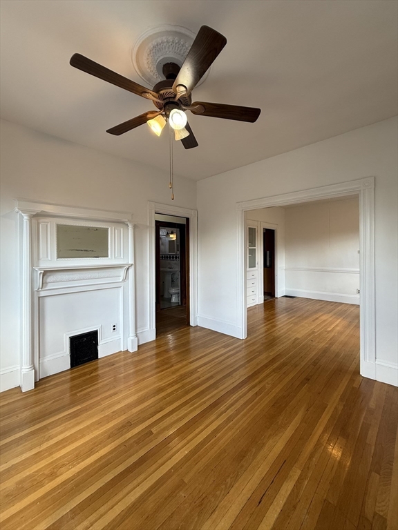 32-34 Etna Street, Unit 2 Boston, MA 02135 - Photo 4 of 12 a view of a livingroom with a fireplace a ceiling fan and wooden floor