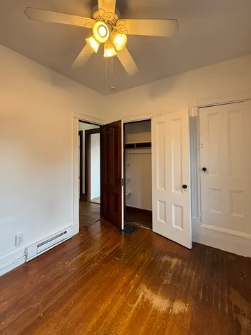 an empty room with wooden floor closet and windows
