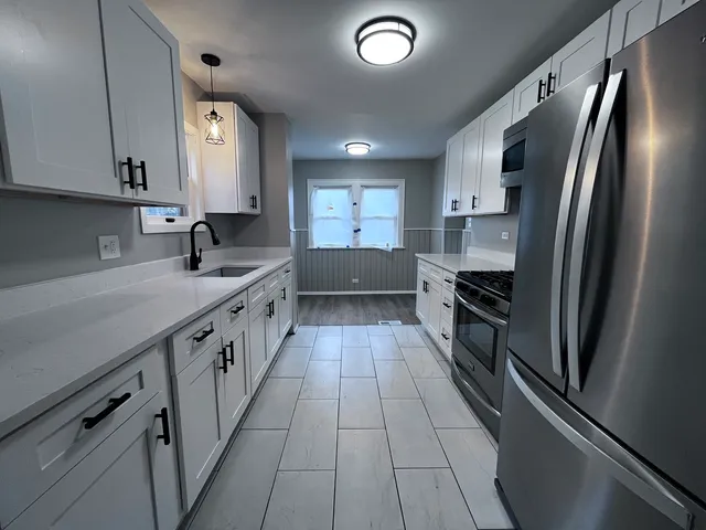 a kitchen with stainless steel appliances granite countertop a refrigerator a sink dishwasher a stove and white countertops with wooden floor