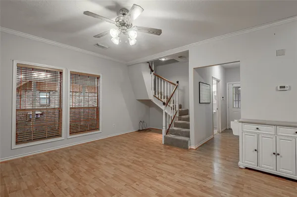 a view of an empty room with wooden floor and a ceiling fan