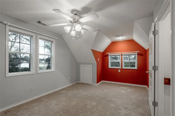 an empty room with chandelier fan and windows