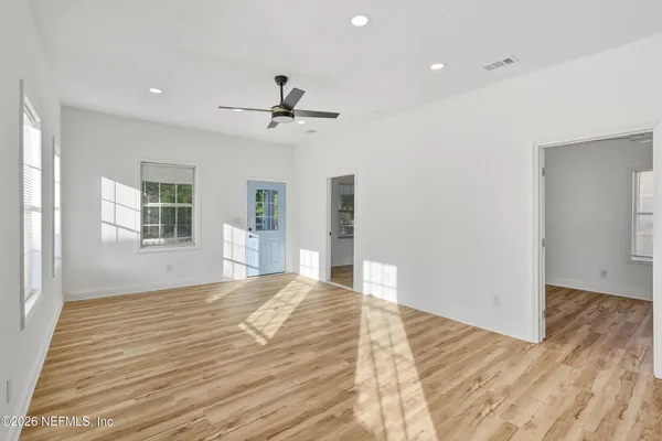 a view of empty room with wooden floor and fan