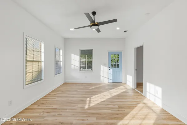 a view of empty room with wooden floor and fan