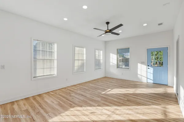 a view of empty room with wooden floor and fan