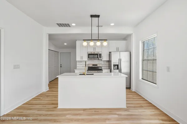 a view of kitchen with refrigerator stove and wooden floor
