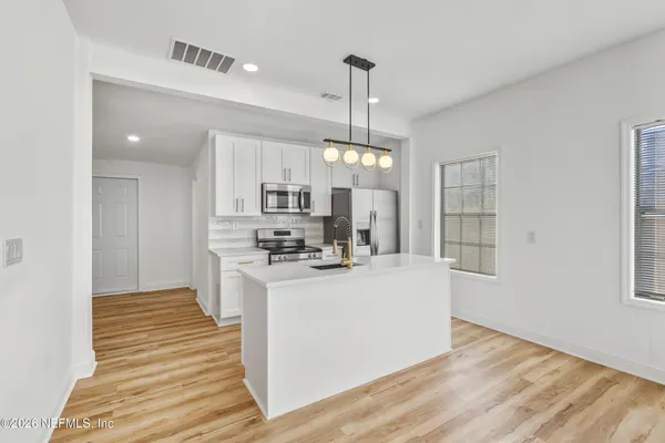 a view of a kitchen with kitchen island a sink wooden floor and a window