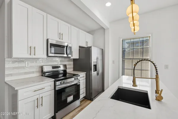 a kitchen with granite countertop a sink stainless steel appliances and white cabinets