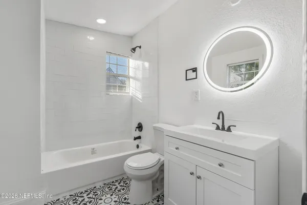 a bathroom with a toilet a sink a mirror and bathtub