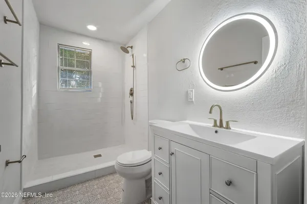 a bathroom with a toilet a sink a mirror and shower
