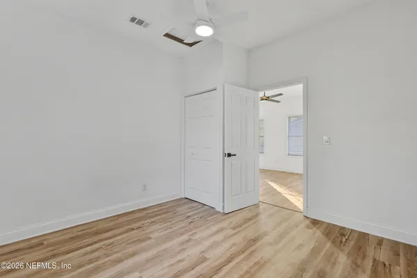 a view of an empty room with wooden floor and a ceiling fan