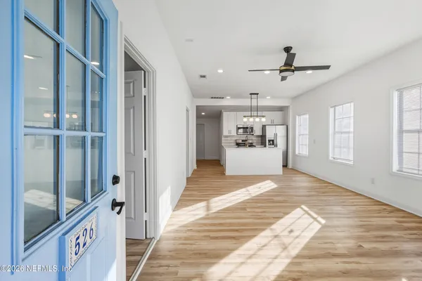 a view of a hallway with wooden floor and a kitchen