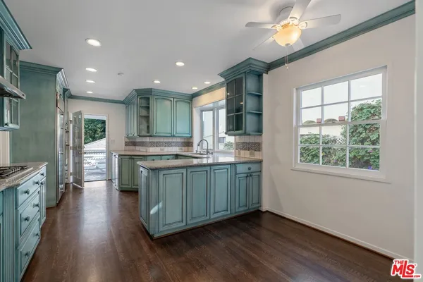 a kitchen with stainless steel appliances granite countertop wooden floors and view of living room