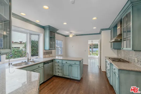a kitchen with stainless steel appliances granite countertop a sink a stove and a wooden floors
