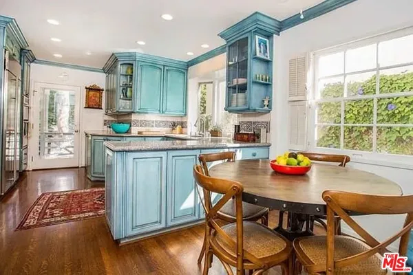a kitchen with stainless steel appliances granite countertop a table chairs sink and cabinets