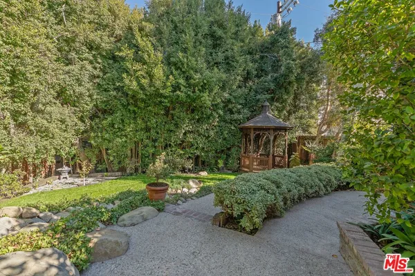 a view of a garden with a bench under an umbrella