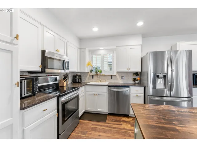 a kitchen with granite countertop a refrigerator stove top oven and sink