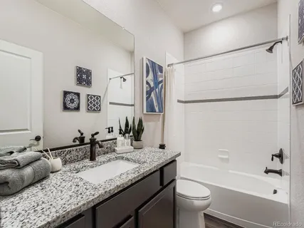 a bathroom with a granite countertop sink a toilet and a bathtub