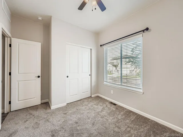 an empty room with chandelier fan and windows