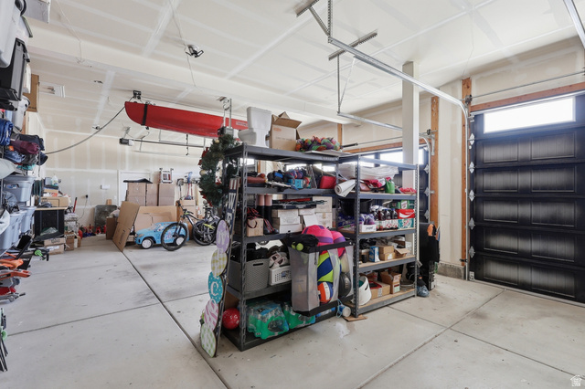 10676 Urban Rdg Cove South Jordan, UT 84095 - Photo 22 of 48 Spacious garage featuring a concrete floor, overhead storage systems, and a dark-paneled garage door with an upper window