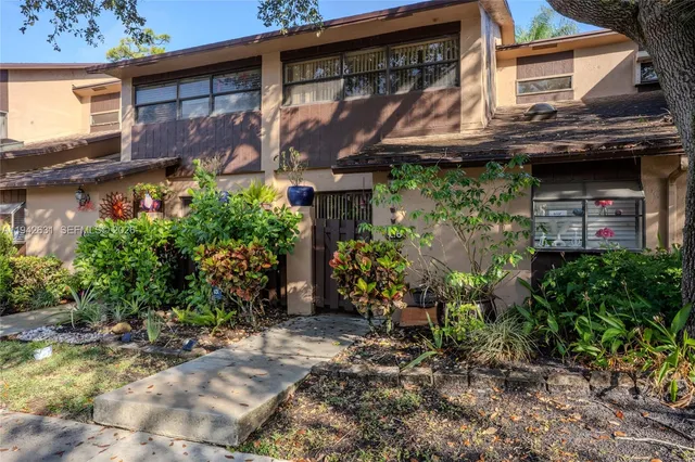 a view of a house with a small yard and potted plants