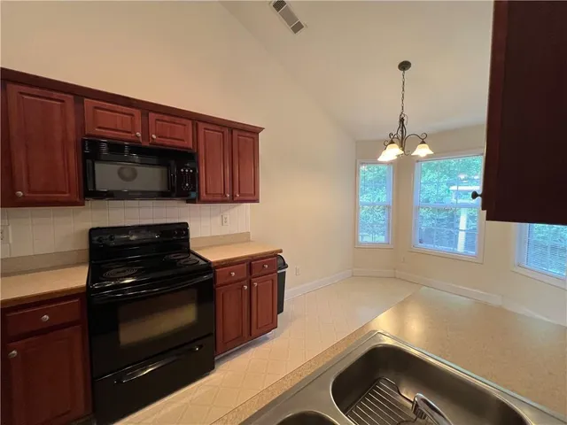 a kitchen with stainless steel appliances granite countertop a stove refrigerator a sink dishwasher with wooden cabinets and dining table