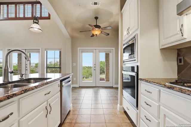 a kitchen with stainless steel appliances granite countertop a stove a sink and a granite counter tops with white cabinets
