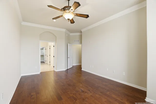 an empty room with wooden floor and a ceiling fan