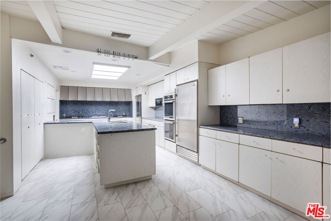 1460 Carla Ridge Beverly Hills, CA 90210 - Photo 16 of 20 a large kitchen with stainless steel appliances and white cabinets