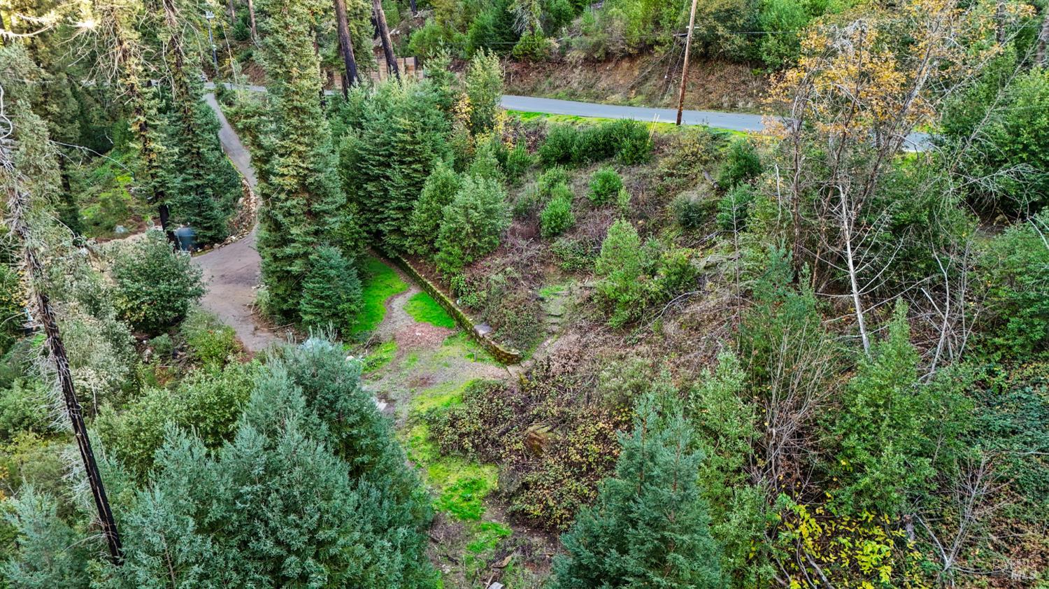 an aerial view of residential house with outdoor space and trees all around