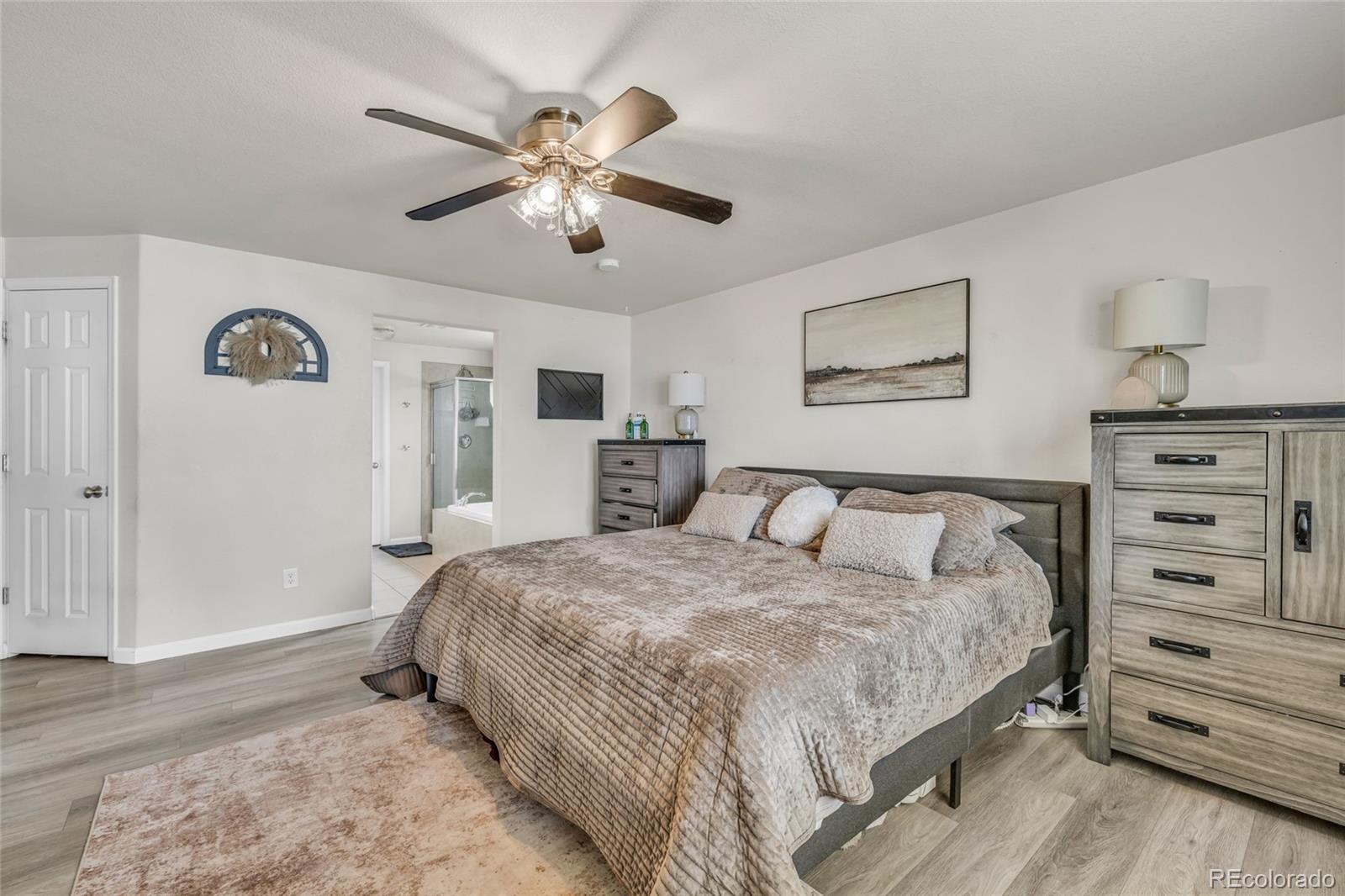 6132 Graden Street Frederick, CO 80530 - Photo 10 of 28 a spacious bedroom with a bed and a chandelier