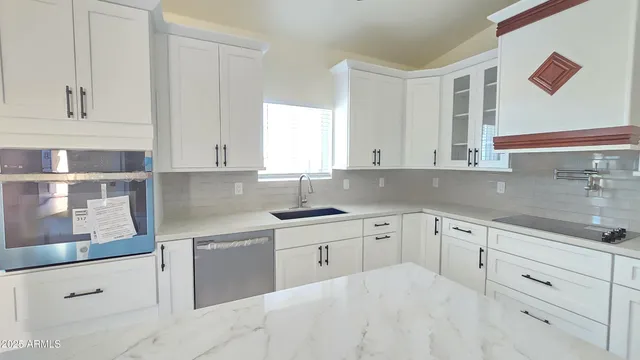 a kitchen with white cabinets and sink