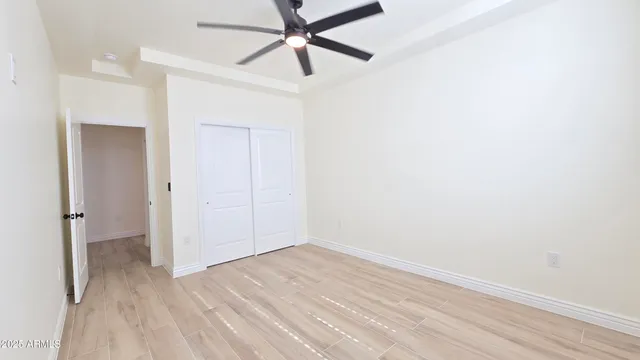 an empty room with wooden floor and ceiling fan